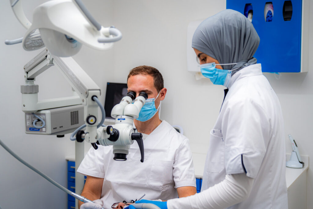 Tandarts en assistente werken met een tandheelkundige microscoop in de behandelkamer in Schiedam